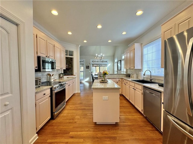 kitchen with a kitchen island, appliances with stainless steel finishes, sink, decorative backsplash, and light stone countertops