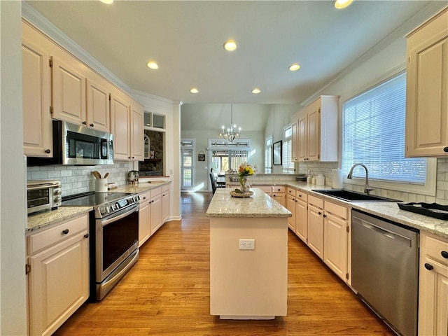 kitchen featuring stainless steel appliances, a center island, sink, and light stone countertops