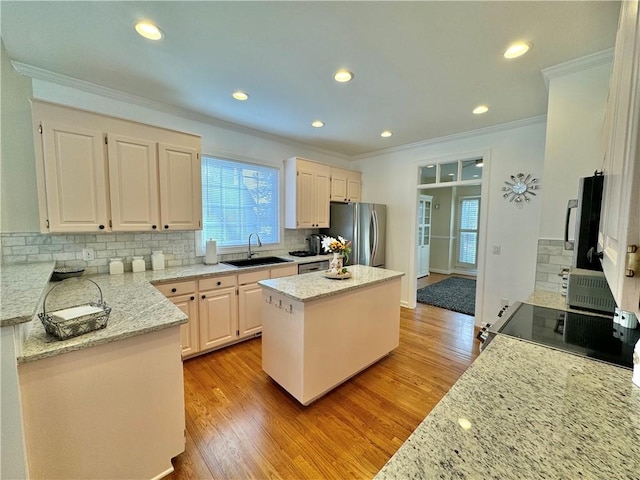 kitchen with sink, crown molding, appliances with stainless steel finishes, light stone counters, and a kitchen island