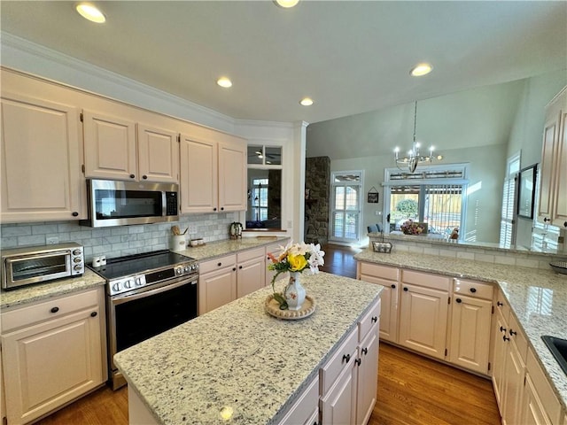 kitchen featuring pendant lighting, stainless steel appliances, light stone countertops, and a wealth of natural light