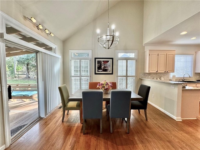 dining room with lofted ceiling, a healthy amount of sunlight, and light hardwood / wood-style flooring