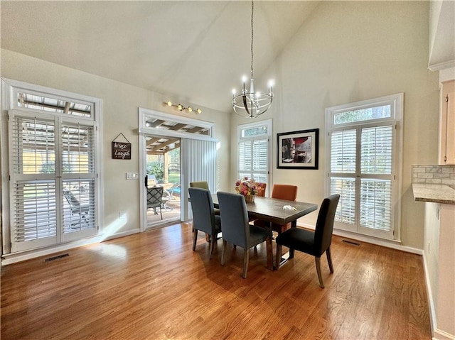 dining area with high vaulted ceiling, light hardwood / wood-style flooring, and a notable chandelier