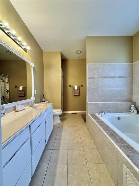 bathroom featuring tile patterned flooring, vanity, toilet, and tiled tub