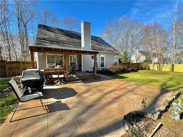 rear view of property featuring a patio, a deck, and a lawn