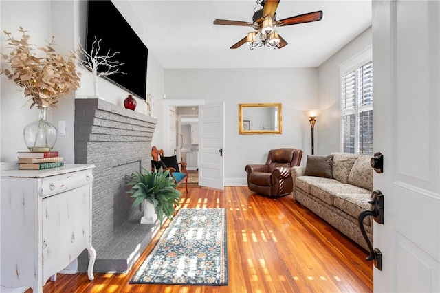 living room featuring a fireplace, wood-type flooring, and ceiling fan