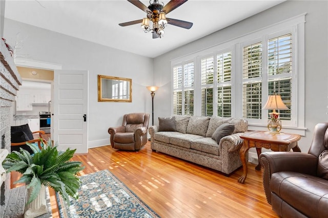 living room with hardwood / wood-style flooring, a brick fireplace, and ceiling fan