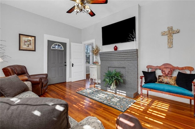 living room with hardwood / wood-style flooring, a brick fireplace, and ceiling fan