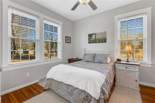 bedroom featuring ceiling fan, hardwood / wood-style floors, and multiple windows