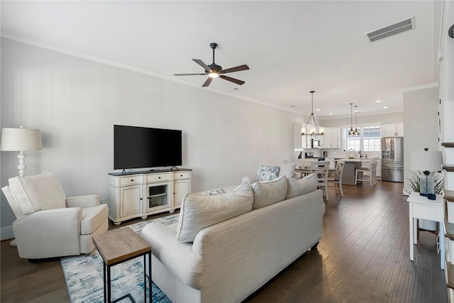 living room featuring ornamental molding, dark hardwood / wood-style floors, and ceiling fan with notable chandelier