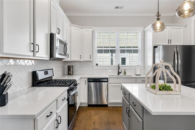 kitchen featuring pendant lighting, white cabinetry, sink, decorative backsplash, and stainless steel appliances