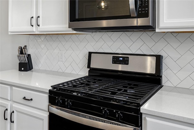 kitchen featuring decorative backsplash, light stone countertops, white cabinets, and appliances with stainless steel finishes