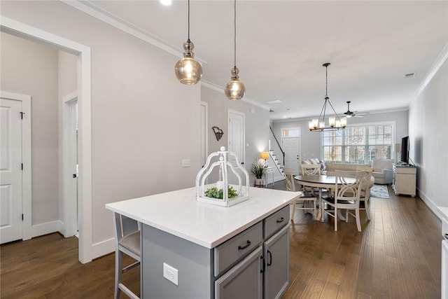 kitchen with decorative light fixtures, gray cabinetry, dark hardwood / wood-style flooring, ornamental molding, and a center island