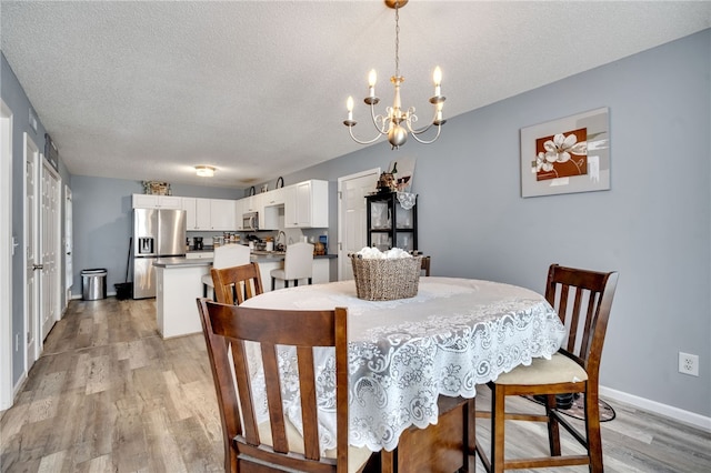 dining room featuring a chandelier, a textured ceiling, and light hardwood / wood-style flooring