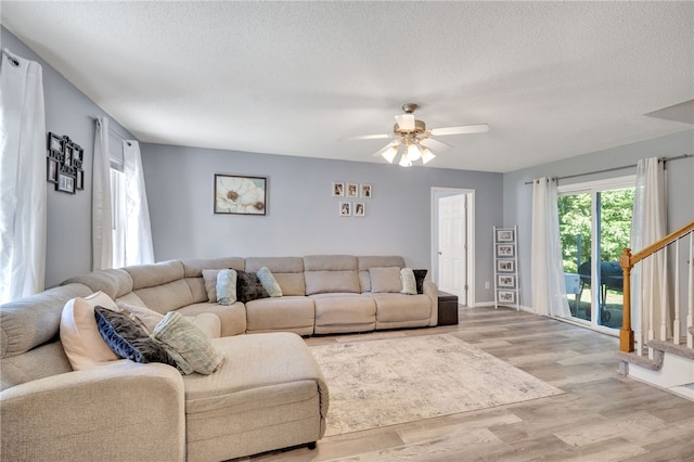 living room with ceiling fan, a textured ceiling, and light wood-type flooring