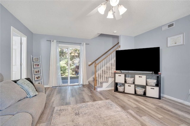 living room with ceiling fan, light hardwood / wood-style floors, and a textured ceiling