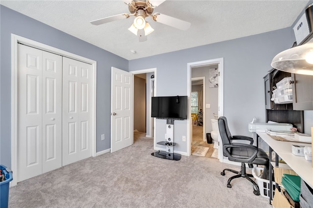 office space featuring light carpet, ceiling fan, and a textured ceiling