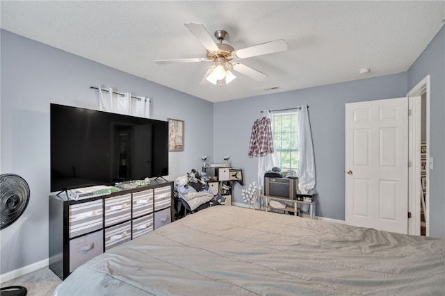 bedroom with ceiling fan, carpet flooring, and a textured ceiling