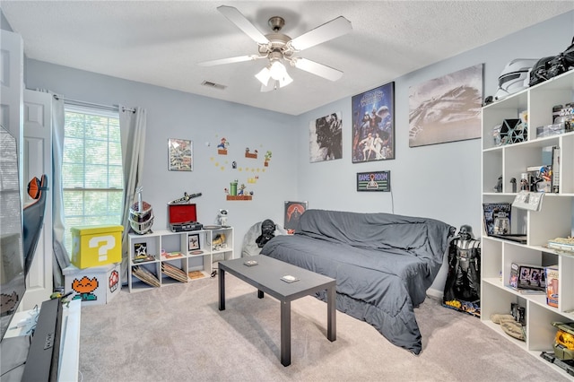 carpeted bedroom featuring ceiling fan and a textured ceiling