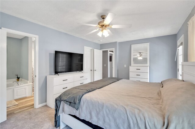 bedroom with a textured ceiling, light colored carpet, ceiling fan, and ensuite bathroom