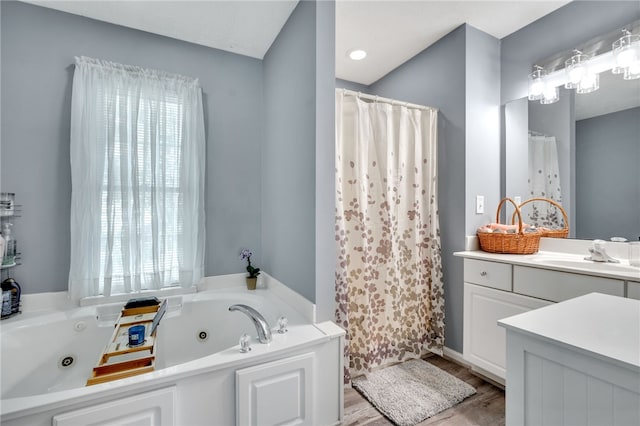 bathroom with vanity, hardwood / wood-style flooring, plenty of natural light, and a tub