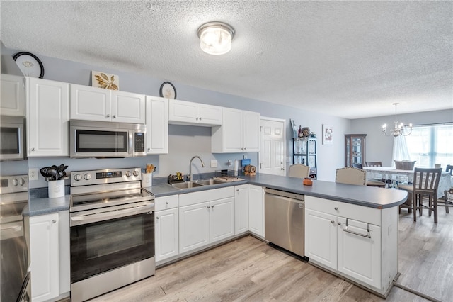 kitchen featuring sink, white cabinetry, decorative light fixtures, kitchen peninsula, and stainless steel appliances