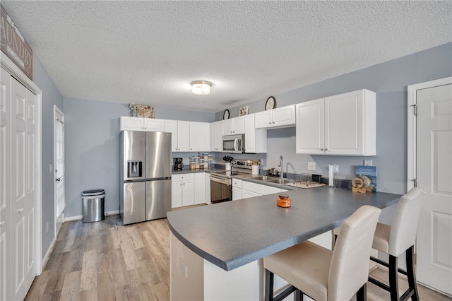 kitchen with white cabinetry, appliances with stainless steel finishes, a kitchen bar, and kitchen peninsula