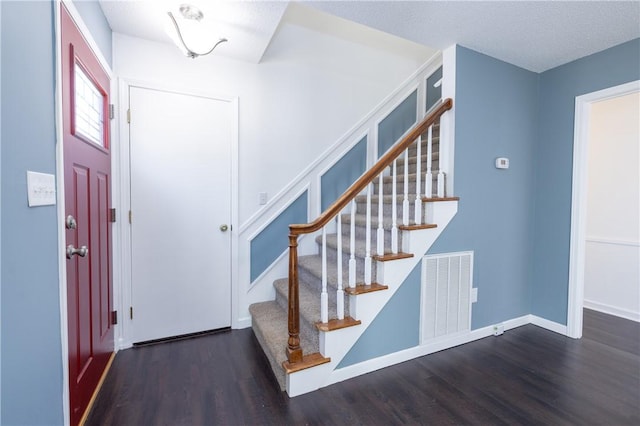 entrance foyer with dark wood-type flooring and a textured ceiling