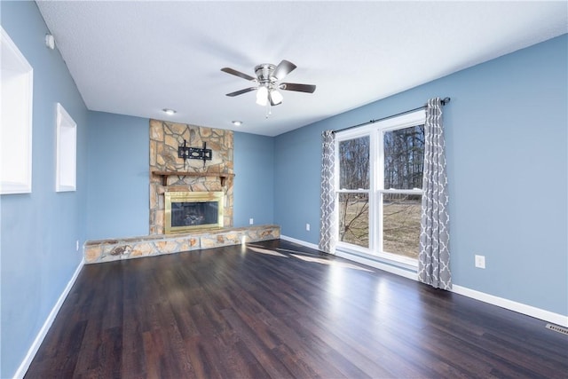 unfurnished living room with hardwood / wood-style floors, a stone fireplace, and a healthy amount of sunlight