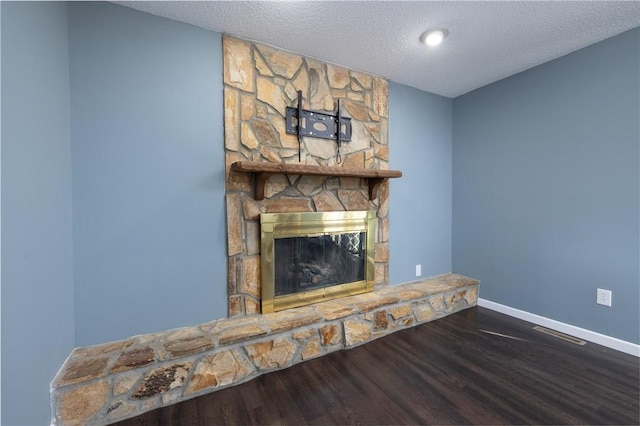 unfurnished living room featuring a stone fireplace, hardwood / wood-style floors, and a textured ceiling