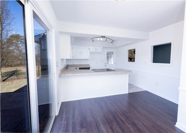 kitchen featuring sink, plenty of natural light, dark hardwood / wood-style floors, white cabinets, and kitchen peninsula