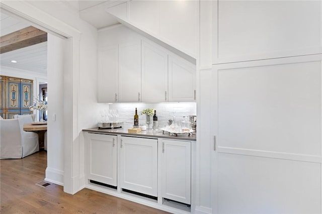 bar featuring white cabinetry, light hardwood / wood-style flooring, and beamed ceiling