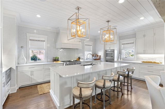 kitchen featuring a kitchen island with sink, sink, white cabinetry, and a kitchen breakfast bar