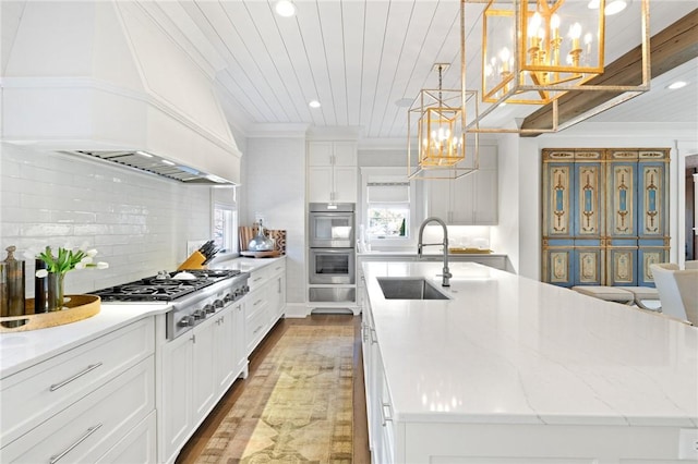 kitchen with white cabinetry, a large island, sink, and hanging light fixtures