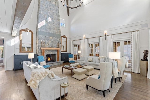 living room with beamed ceiling, a stone fireplace, high vaulted ceiling, and french doors