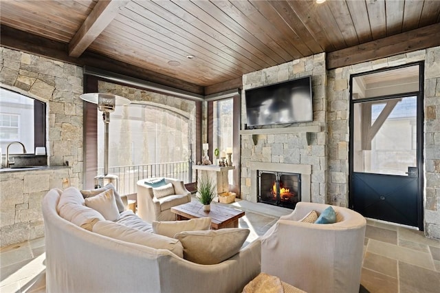 living room with beamed ceiling, sink, wood ceiling, and a fireplace