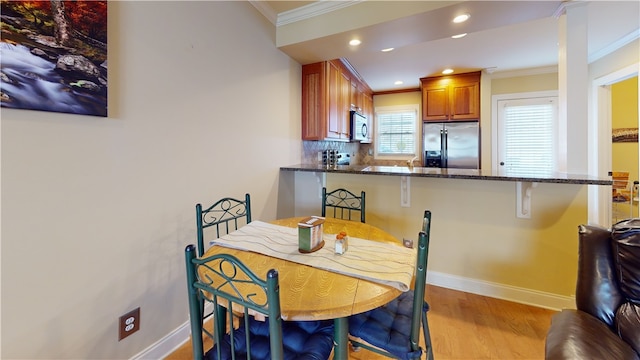 dining space featuring crown molding and light hardwood / wood-style floors