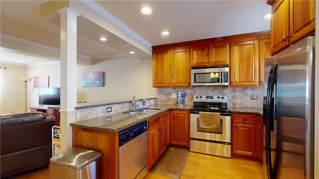 kitchen featuring sink, appliances with stainless steel finishes, kitchen peninsula, dark stone counters, and light wood-type flooring