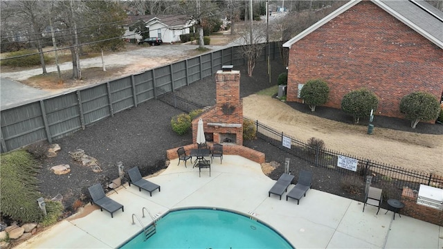 view of swimming pool with an outdoor brick fireplace and a patio area