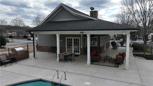 back of house featuring a fenced in pool, a patio area, french doors, and exterior kitchen