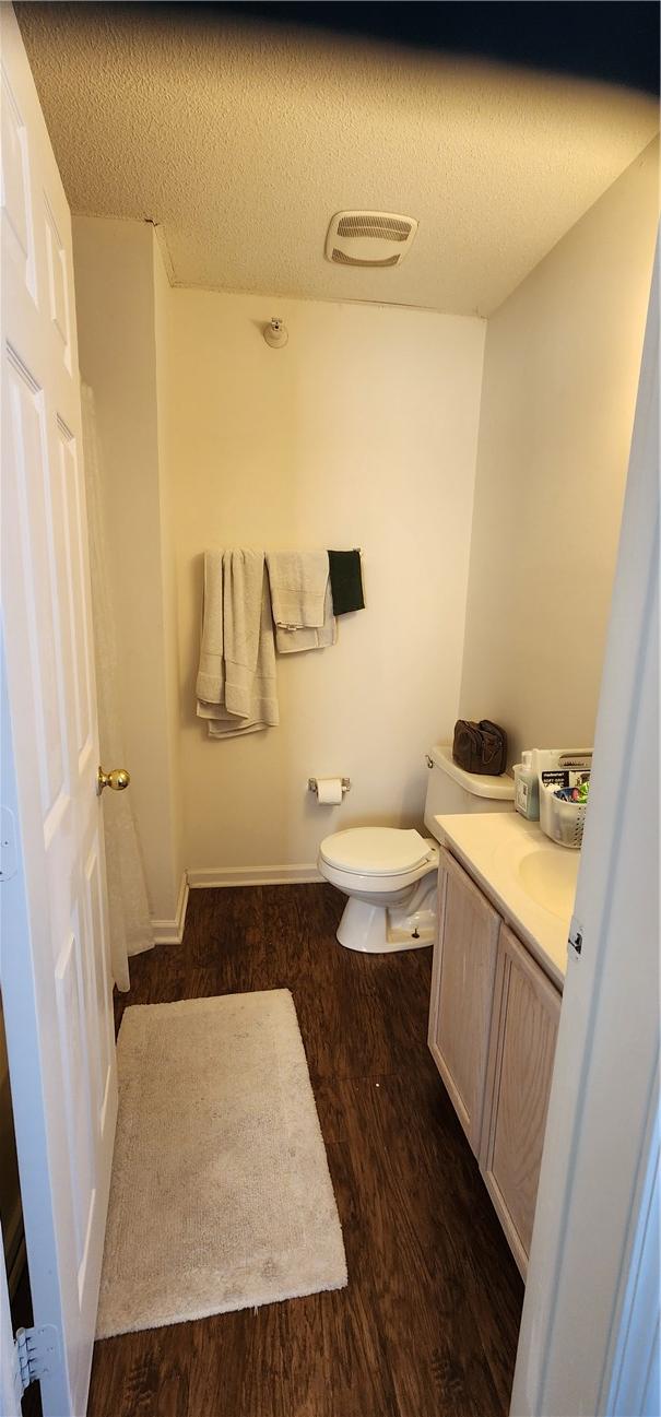 bathroom with vanity, toilet, hardwood / wood-style floors, and a textured ceiling