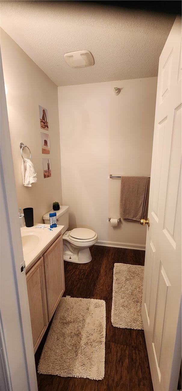 bathroom featuring vanity, hardwood / wood-style flooring, toilet, and a textured ceiling