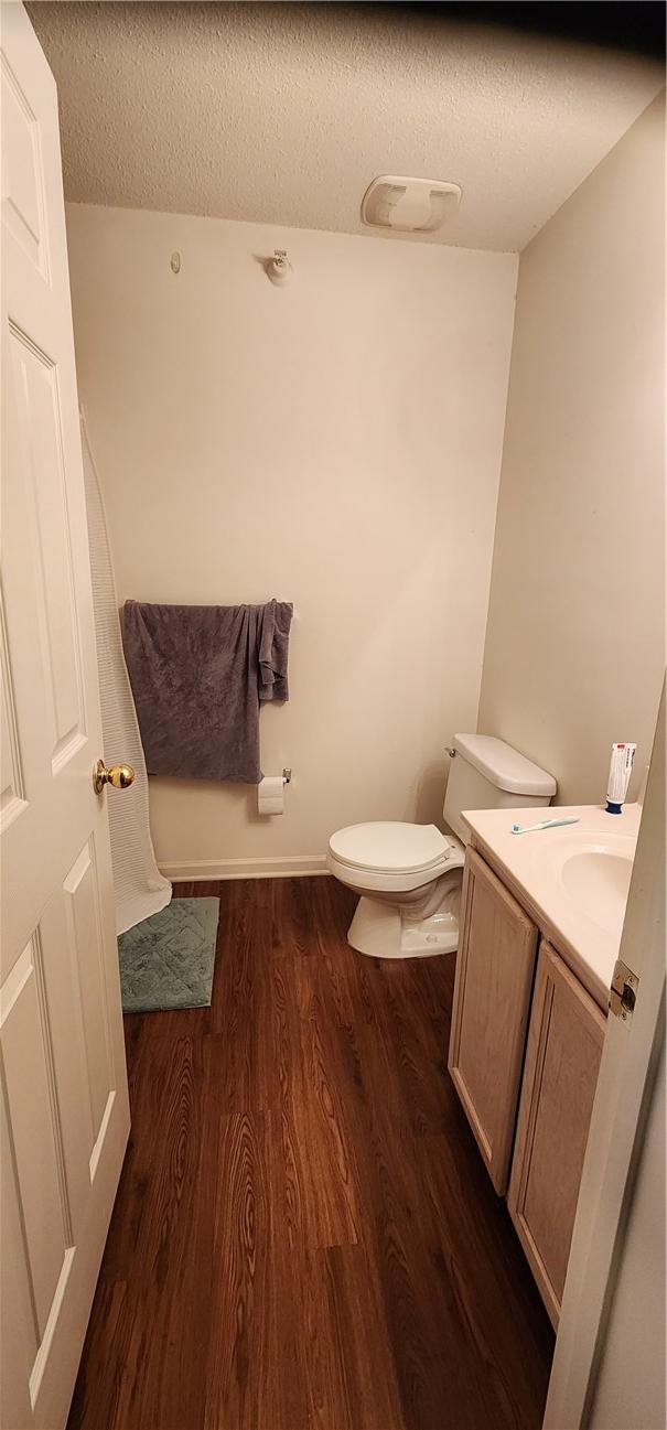 bathroom featuring vanity, hardwood / wood-style floors, toilet, and a textured ceiling