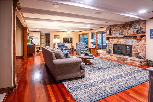 living room with beamed ceiling, a stone fireplace, and hardwood / wood-style floors