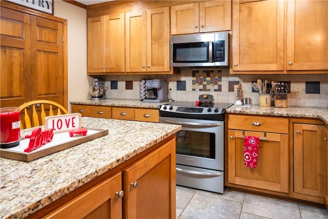 kitchen with light stone counters, decorative backsplash, and stainless steel appliances