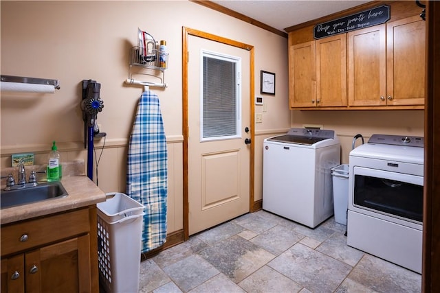 laundry room featuring cabinets, washing machine and dryer, sink, and crown molding