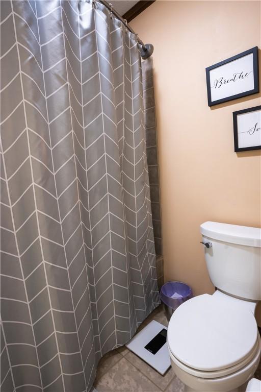 bathroom featuring tile patterned flooring, toilet, and a shower with shower curtain