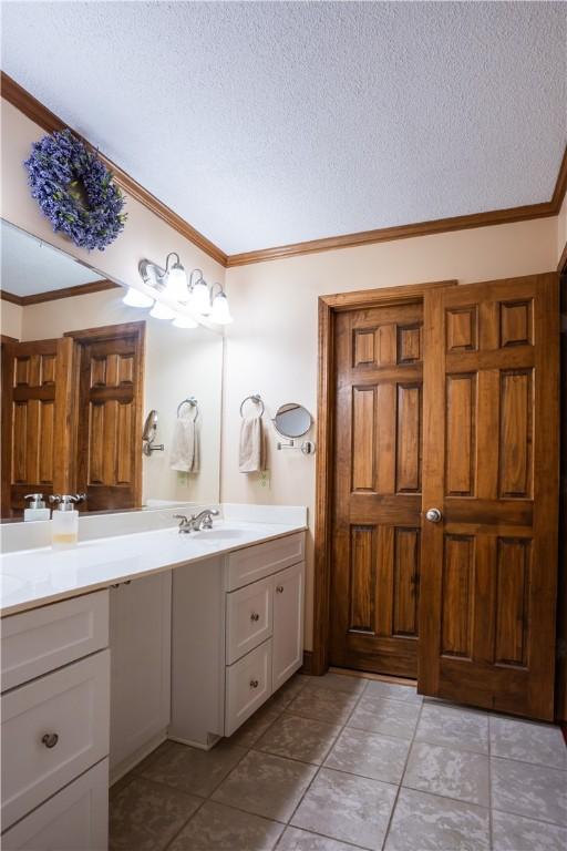 bathroom featuring crown molding, tile patterned floors, vanity, and a textured ceiling