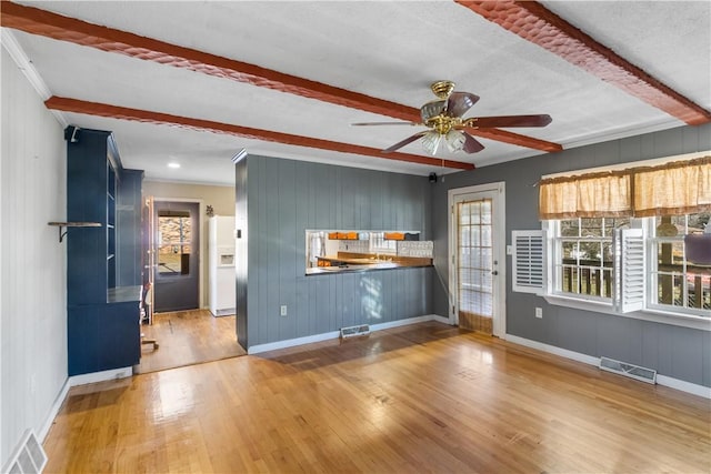 unfurnished living room featuring beamed ceiling, crown molding, hardwood / wood-style flooring, and ceiling fan