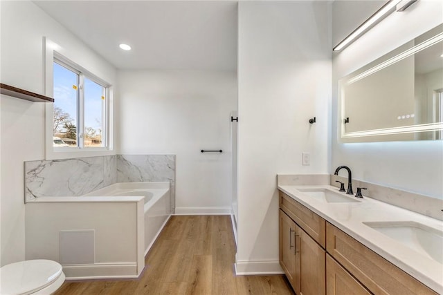 bathroom with hardwood / wood-style flooring, vanity, toilet, and a bathtub