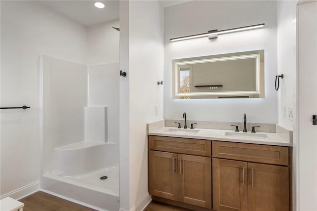 bathroom with hardwood / wood-style flooring, vanity, and walk in shower